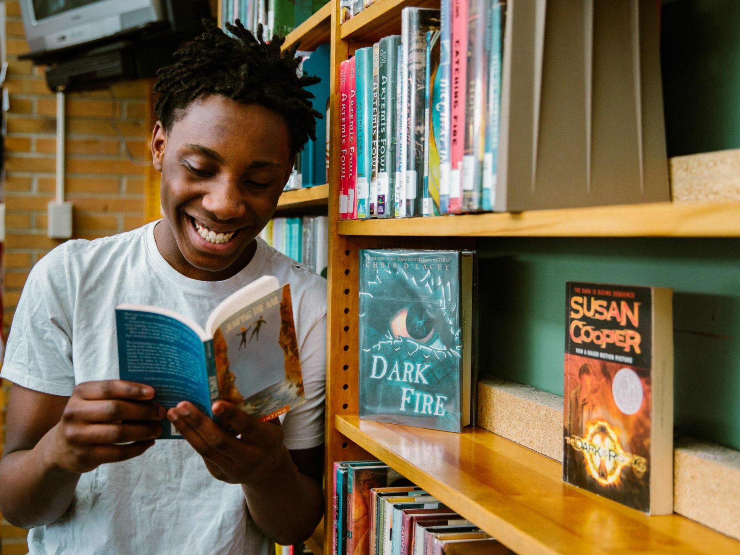 Garçon lisant un livre dans une bibliothèque