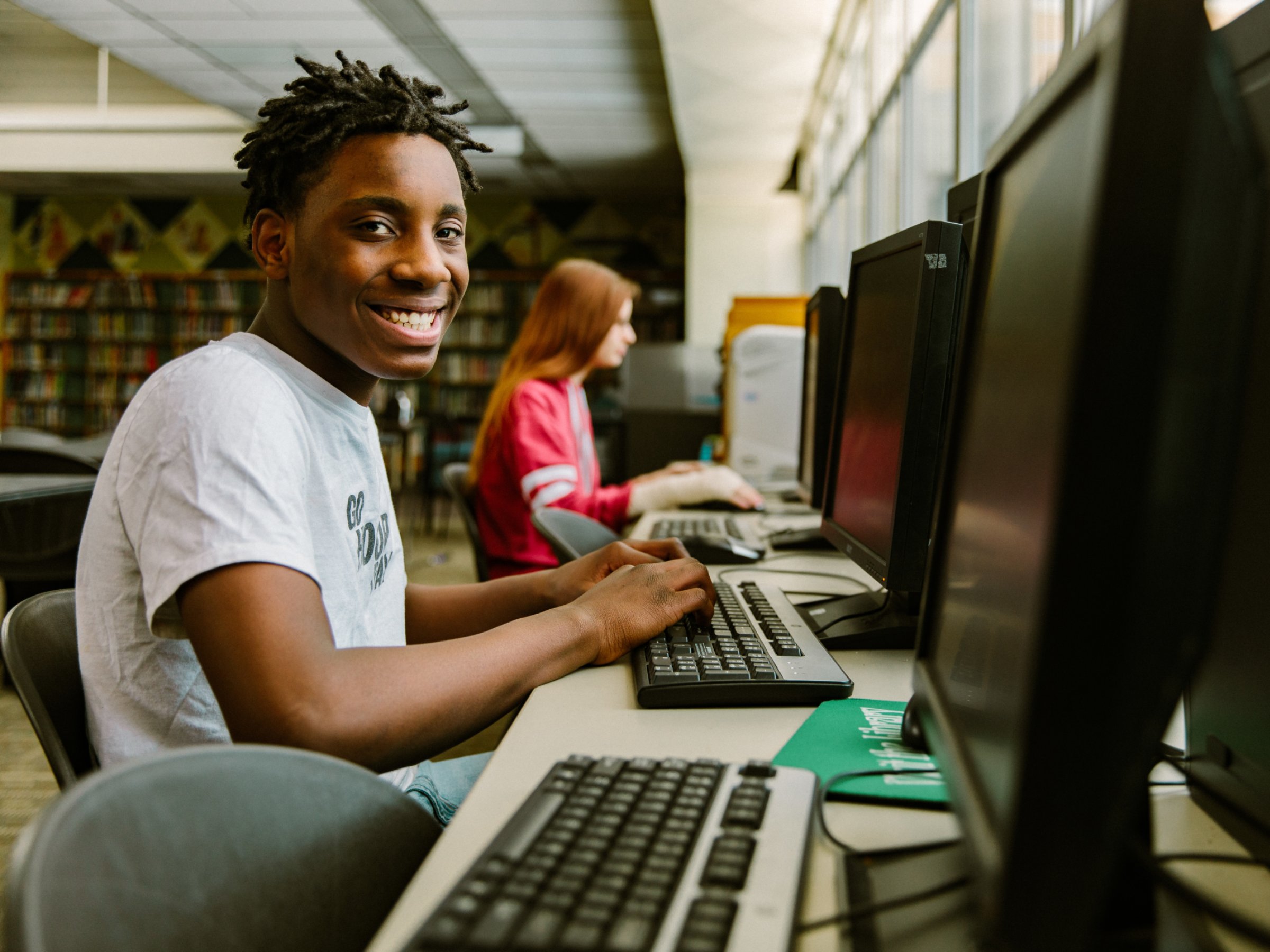 صبي يبتسم للكمبيوتر في المكتبة
