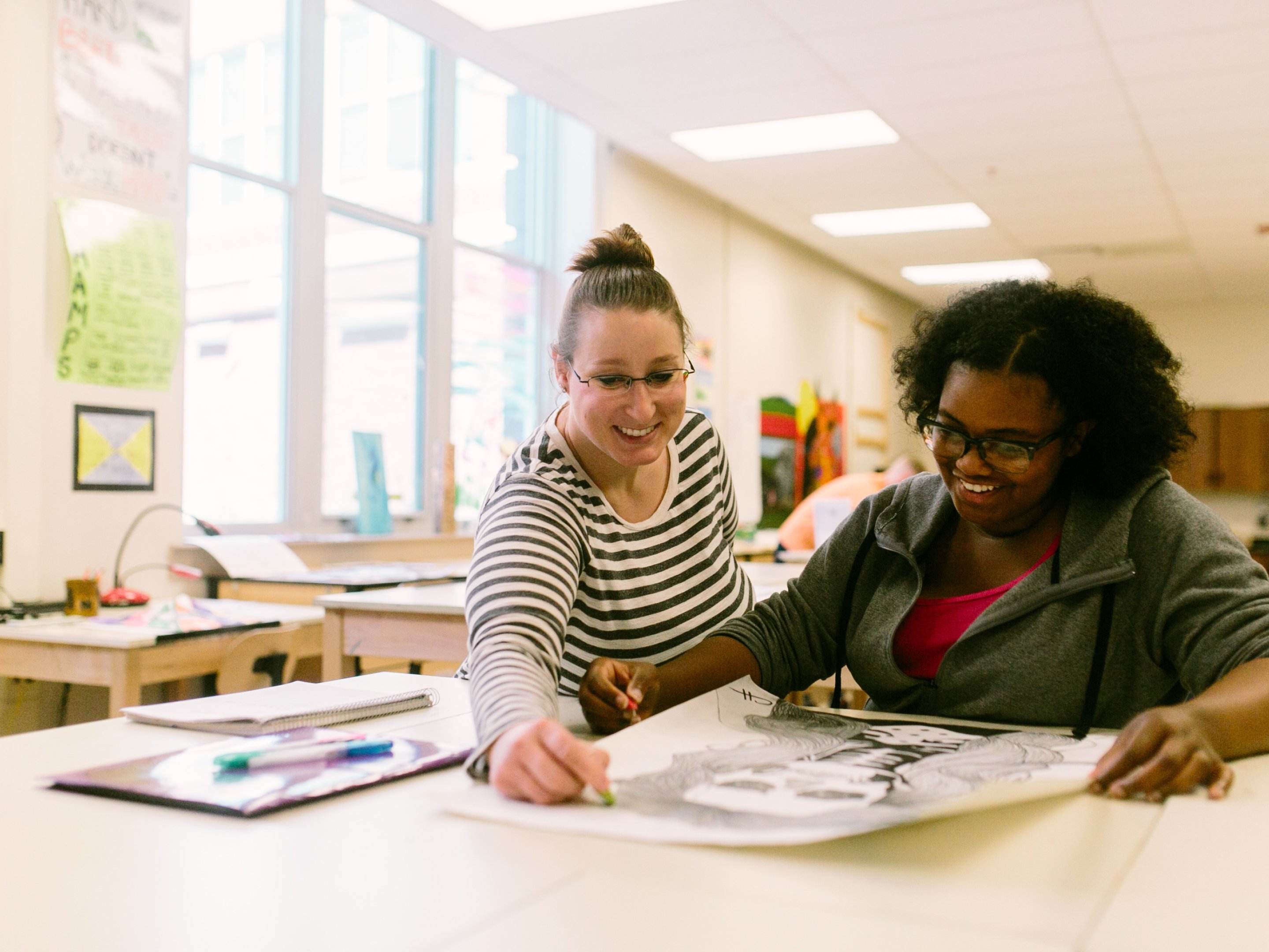 Un profesor de arte ayuda a un alumno con su dibujo en clase de arte