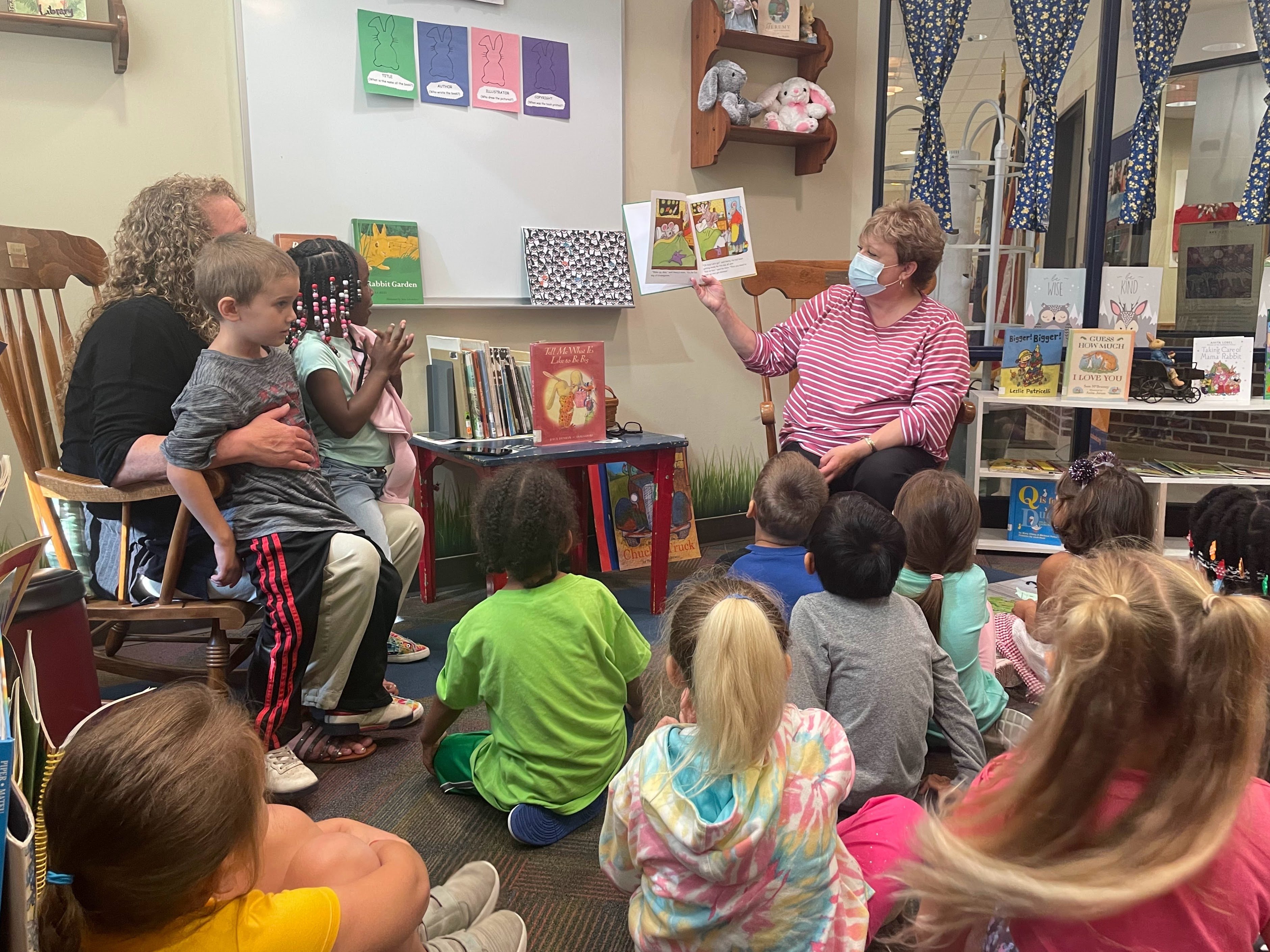 La Sra. Ford leyendo a la clase de preescolar de la Sra. Gildea en la zona de la madriguera de conejos de la biblioteca.