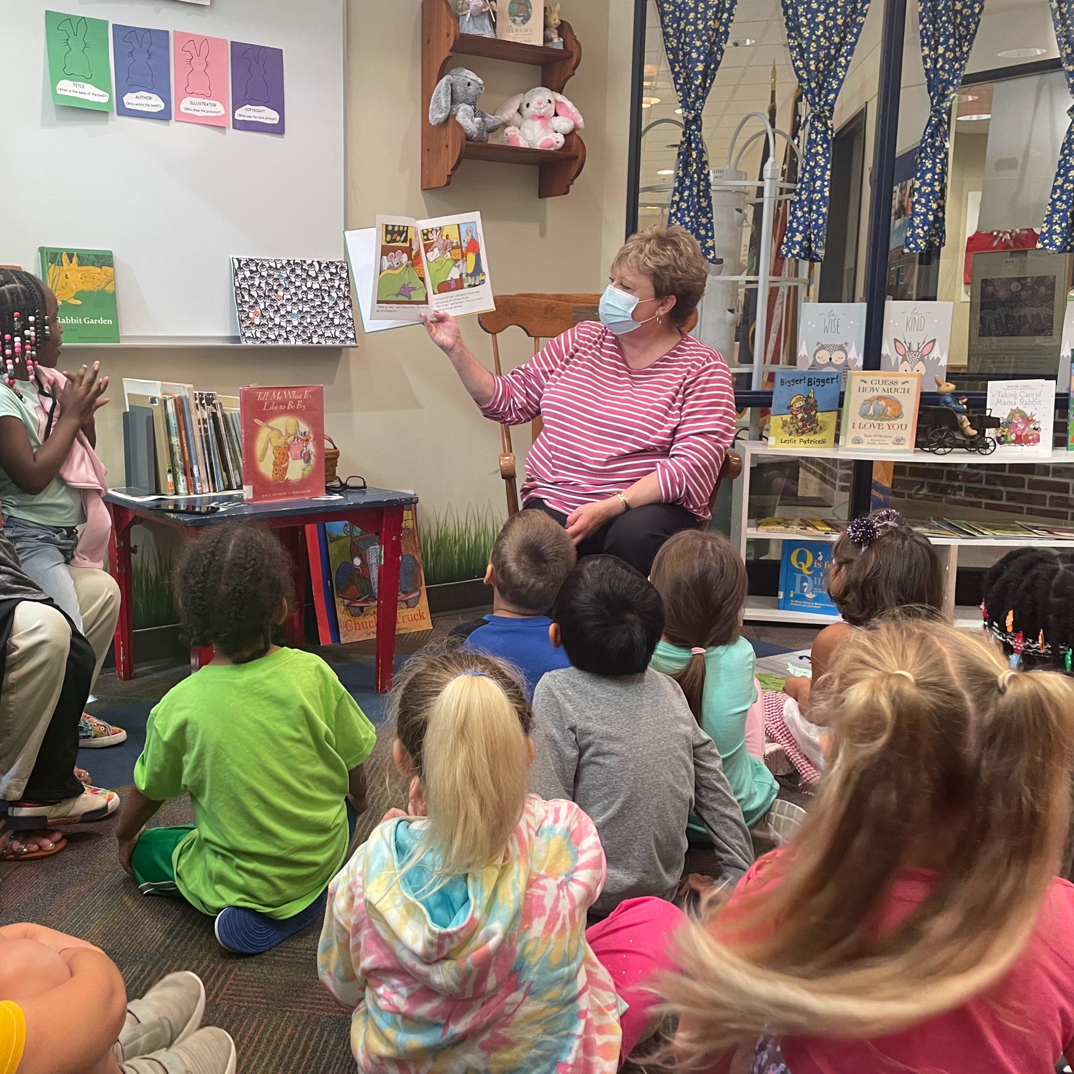 Mme Ford fait la lecture à la classe de maternelle de Mme Gildea dans le terrier de la bibliothèque.